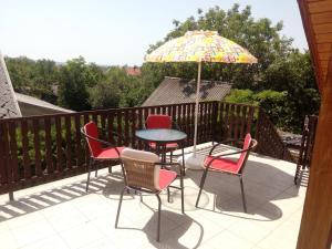 patio z krzesłami, stołem i parasolem w obiekcie Marika apartman w mieście Balatongyörök