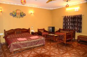 a bedroom with two beds and chairs and a television at Nakhrali Dhani Resort in Indore