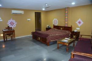 インドールにあるNakhrali Dhani Resortのベッドルーム1室(ベッド1台、テーブル、椅子付)