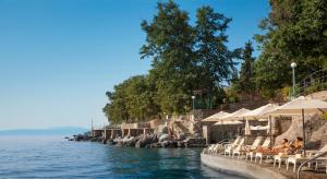 a pool with chairs and umbrellas next to the water at Hotel Excelsior - by Liburnia Hotels & Villas in Lovran