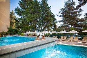 zwei Personen sitzen im Pool eines Resorts in der Unterkunft Hotel Excelsior - Liburnia in Lovran