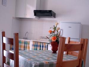 una cocina con una mesa con un jarrón de flores. en Casa Vacanze Margherita en Locogrande