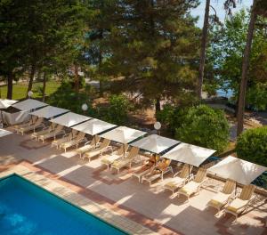 a group of white umbrellas and chairs next to a pool at Hotel Excelsior - Liburnia in Lovran