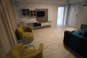 a living room with yellow chairs and a television at Hotel Dedal in Mamaia Sat/Năvodari