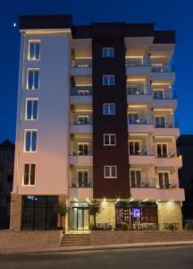 een hoog gebouw 's nachts met lichten aan bij Hotel 219 Budva in Budva