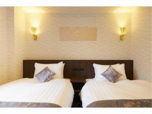 two beds in a hotel room with lights on the wall at Rinn Miyagawacho Grande in Kyoto