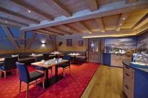 ein Restaurant mit Holzdecken, Tischen und Stühlen in der Unterkunft Hotel Garni Zugspitz in Farchant
