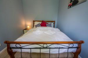 Schlafzimmer mit einem Bett mit weißer Bettwäsche und einem roten Kissen in der Unterkunft Apartament Brzozowy Zakątek - 5D Apartamenty in Świeradów-Zdrój