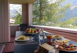 einen Tisch mit Tellern aus Essen auf einem Balkon in der Unterkunft Chesa Kristella in Arosa