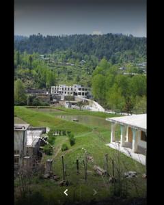 een uitzicht op een park met een gebouw op de achtergrond bij Chikar Highland Resort in Muzaffarabad