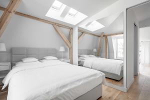 two beds in a white bedroom with two windows at VIU The Roof Apartment in Sopot