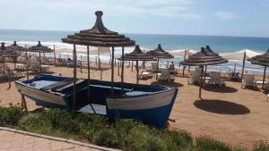 a beach with chairs and umbrellas and boats on the beach at Plage des Nations Prestigia Vue sur mer in Sidi Bouqnadel
