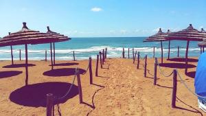 a row of umbrellas on a beach with the ocean at Plage des Nations Prestigia Vue sur mer in Sidi Bouqnadel