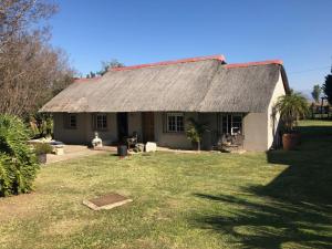 a small white house with a thatched roof at Erin Guesthouse and B&B in Bergville
