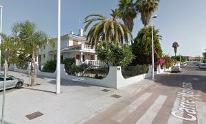 a white house with a palm tree in front of a street at Valencia Sol y Playa in Sagunto