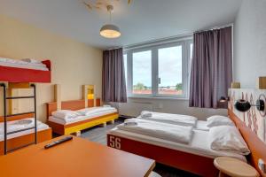 Habitación con 2 camas, mesa y escritorio. en MEININGER Hotel Hamburg City Center, en Hamburgo