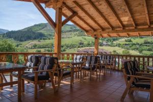 a porch with chairs and tables and a view at Albergue La Cabaña in Turieno
