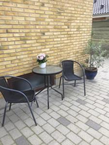 a table with two chairs and a table with flowers on it at Bramming city privat overnatning , ingen morgenmad in Bramming