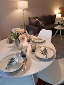 a white table with plates and glasses and flowers on it at 2ndhomes Deluxe Kamppi Center Apartment with Sauna in Helsinki