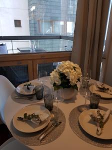a table with plates and glasses and a vase with flowers at 2ndhomes Deluxe Kamppi Center Apartment with Sauna in Helsinki