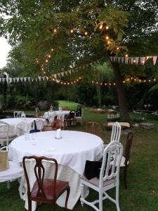 a table with white tables and chairs under a tree with lights at da Gastone in Rivignano