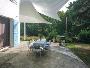une table bleue et des chaises sous un parasol blanc dans l'établissement Holiday home in Bruniquel on the Aveyron river, à Bruniquel