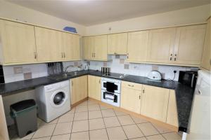 a kitchen with wooden cabinets and a washer and dryer at Marley Mansion Apartments - Borough in Birkenhead