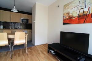 a living room with a television and a table with chairs at Apartament Skwer Gdynia in Gdynia