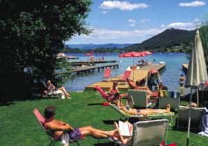 a group of people sitting in lawn chairs at a lake at Ferienwohnungen Schneider in Sankt Kanzian