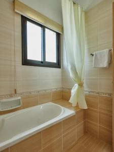 a bathroom with a bath tub and a window at Kyklades Angie Resort in Protaras