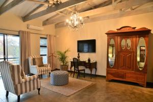 a living room with a chandelier and a wooden cabinet at Bushveld Terrace Safari Hotel, Lodge & Spa in Phalaborwa