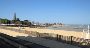 a beach with a fence and people on the beach at Petit nid à 50m de la plage au coeur de Fouras in Fouras +16 photos