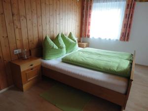 una camera da letto con un letto con cuscini verdi e una finestra di Schöllhorn Judith a Sankt Gallenkirch