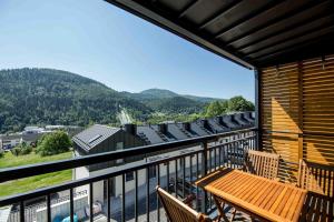 a balcony with a wooden table and chairs and mountains at Apartamenty Słoneczna Góra w spokojnej okolicy - Dream Apart in Szczyrk