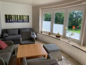 ein Wohnzimmer mit Stühlen, einem Tisch und Fenstern in der Unterkunft Hof Olde Warft in Oldenswort
