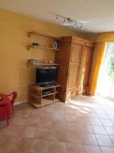 a living room with a tv and a tiled floor at Möwenhaus in Wangerland