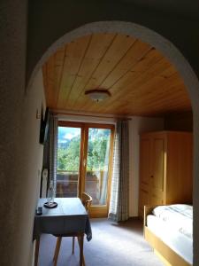 a bedroom with a bed and a table and a window at Frühstückspension Gweil in Sankt Gallenkirch