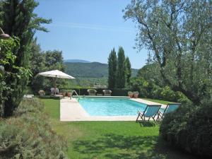een zwembad in een tuin met stoelen en een parasol bij Countryhouse with Pool in Vaison la Romaine in Vaison-la-Romaine