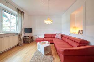 a living room with a red couch and a table at Ferienwohnung AOLI in Gmunden