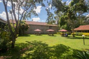 a yard with picnic tables and red umbrellas at Corat Africa Hotel in Nairobi