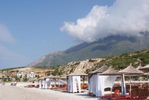 eine Reihe von Hütten an einem Strand mit einem Berg in der Unterkunft Vila Milo in Vuno