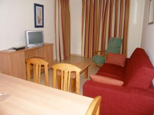 ein Wohnzimmer mit einem Sofa, einem TV und Stühlen in der Unterkunft Apartamentos Cibeles in Roquetas de Mar