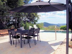 een zwarte tafel en stoelen onder een parasol naast een zwembad bij Delighful Villa in Berlou with Private Swimming Pool in Berlou