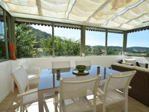 uma sala de jantar com mesa, cadeiras e janelas em Gorgeous Villa in Malaucene with a River Nearby em Malaucène