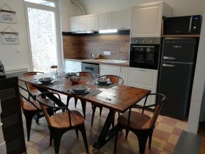 a kitchen with a wooden table with chairs and a black refrigerator at L Alchimie in Fécamp