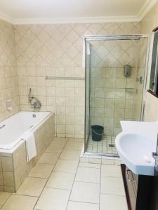 a bathroom with a shower and a tub and a sink at Belmont Guesthouse in Bloemfontein +71 photos