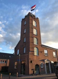un alto edificio di mattoni con una bandiera sopra di De Oude Kazerne Torenkamer a Kaatsheuvel