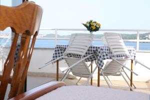 a table with chairs and a vase of flowers on it at Rooms and Apartments Kurtović in Donji Seget