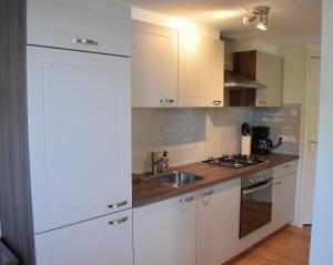 a kitchen with white cabinets and a sink at BenBZuiderzee in Hattem