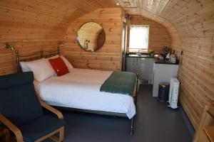 a bedroom with a bed and a chair in a cabin at The Beach Bothies in Valtos
